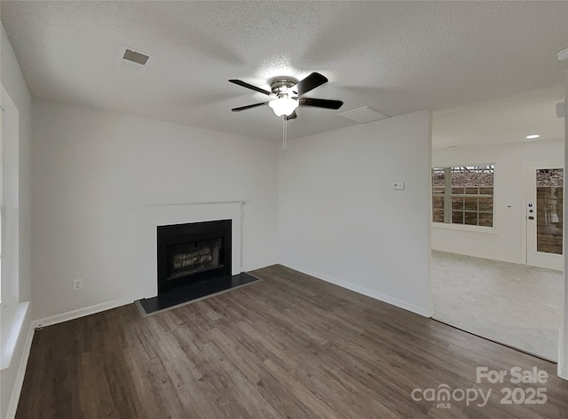 unfurnished living room with a textured ceiling, a fireplace, wood finished floors, and visible vents