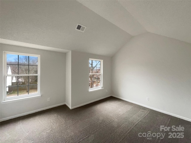 bonus room with dark colored carpet, visible vents, vaulted ceiling, and baseboards