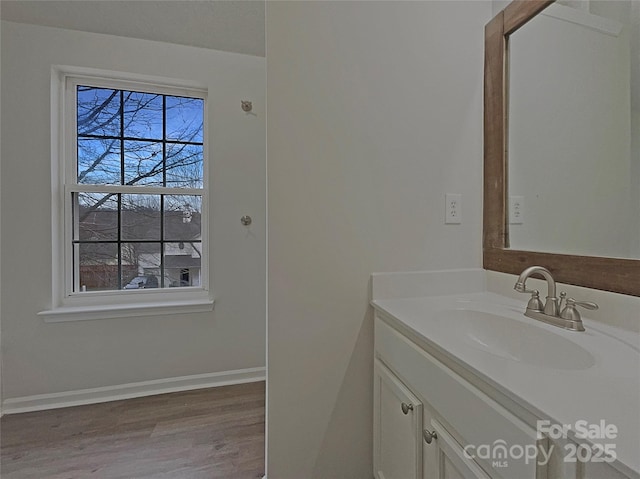 bathroom with wood finished floors, vanity, and baseboards