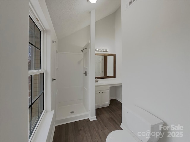 full bathroom featuring walk in shower, visible vents, vaulted ceiling, and wood finished floors