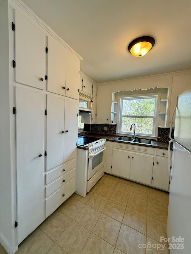 kitchen featuring dark countertops, white appliances, a sink, and open shelves