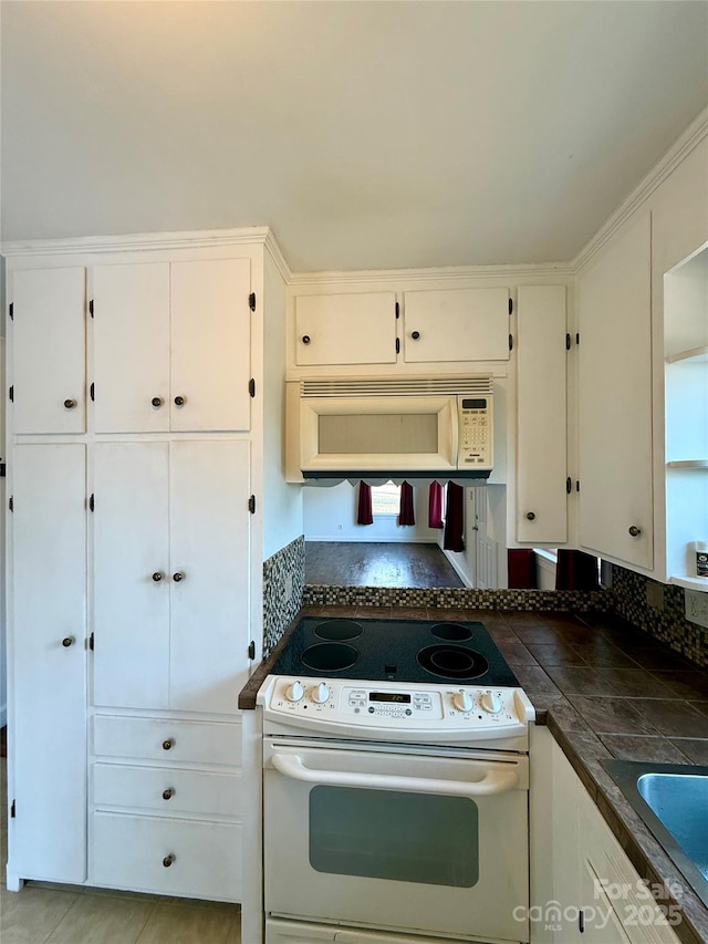 kitchen with white appliances, a sink, and white cabinetry