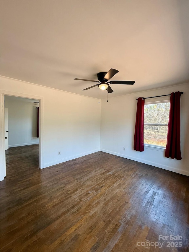 unfurnished room featuring baseboards, dark wood finished floors, and a ceiling fan