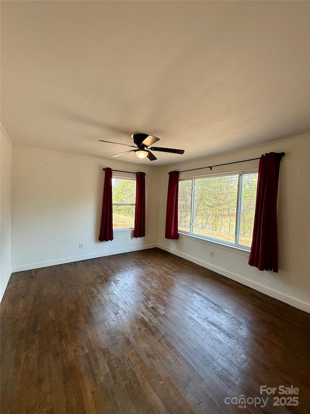 spare room featuring ceiling fan, baseboards, and dark wood-style flooring