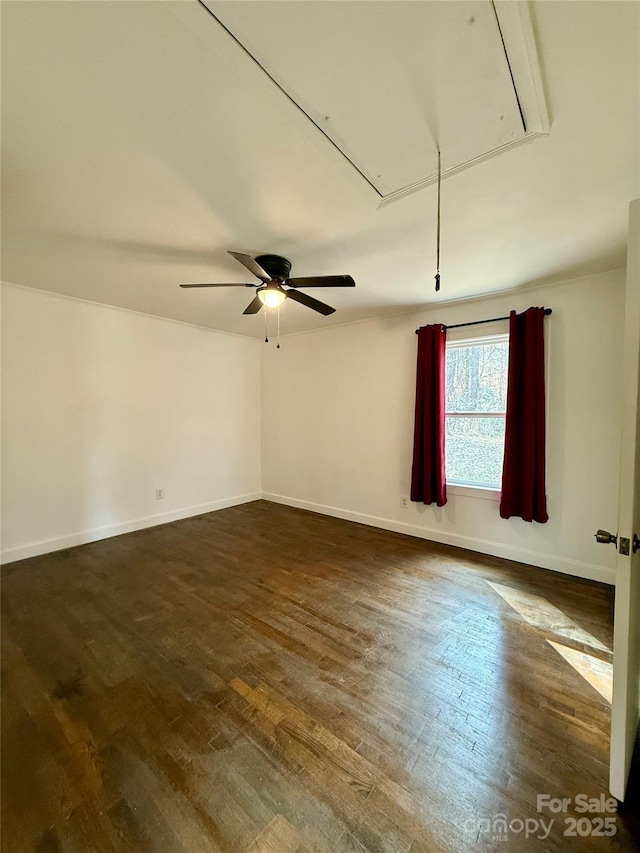 unfurnished room with dark wood-style floors, attic access, and baseboards