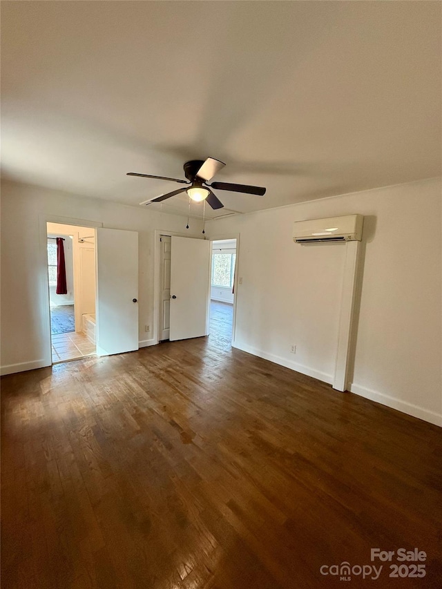 unfurnished bedroom featuring ceiling fan, baseboards, wood finished floors, and an AC wall unit