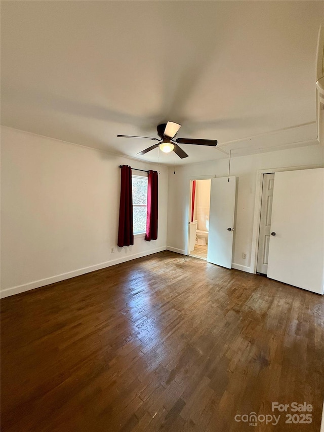 unfurnished bedroom with dark wood-type flooring, attic access, ceiling fan, and baseboards