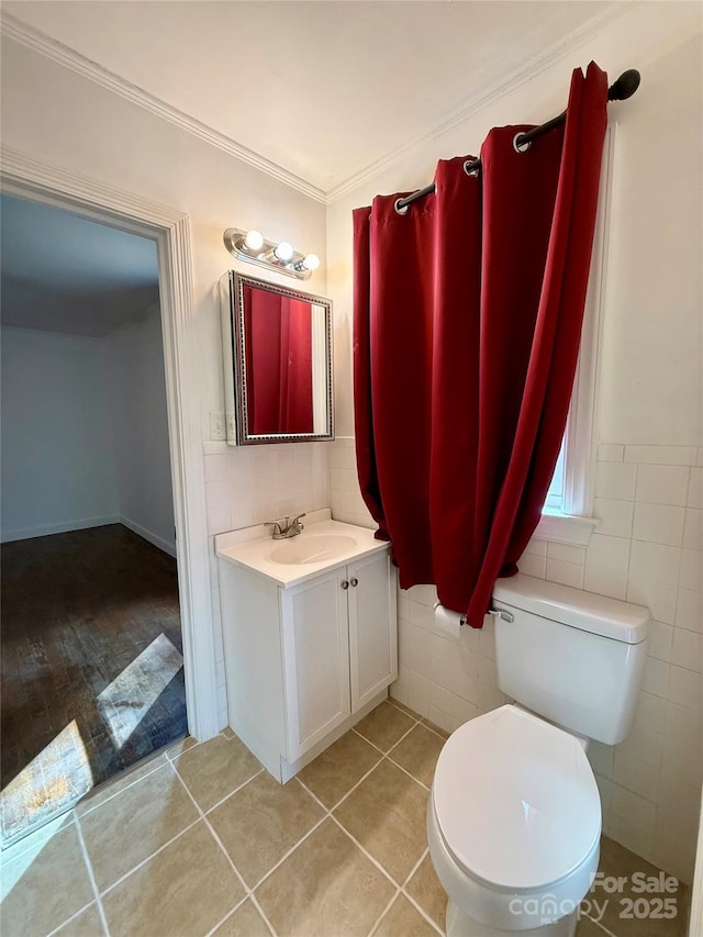 bathroom with crown molding, tile walls, toilet, vanity, and tile patterned floors