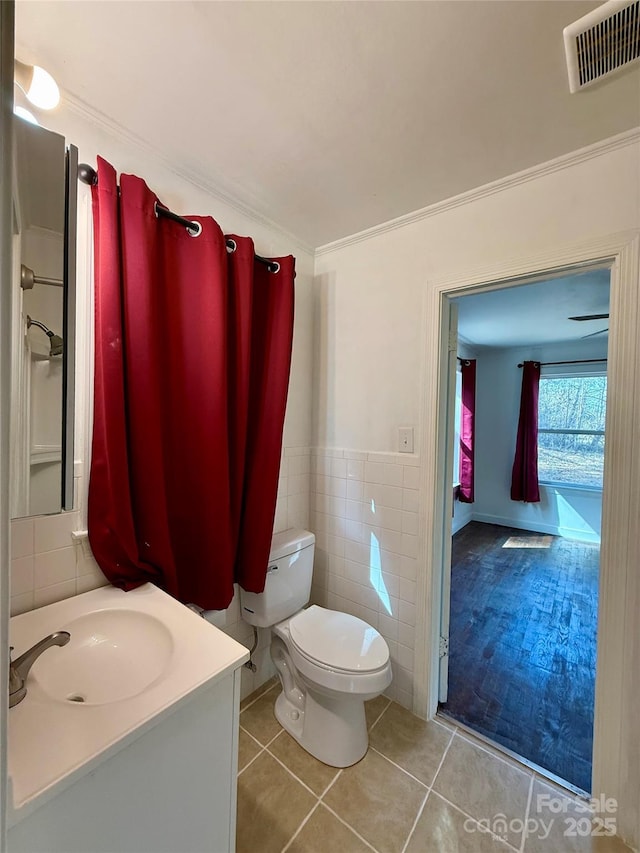 bathroom with tile walls, visible vents, toilet, vanity, and tile patterned flooring