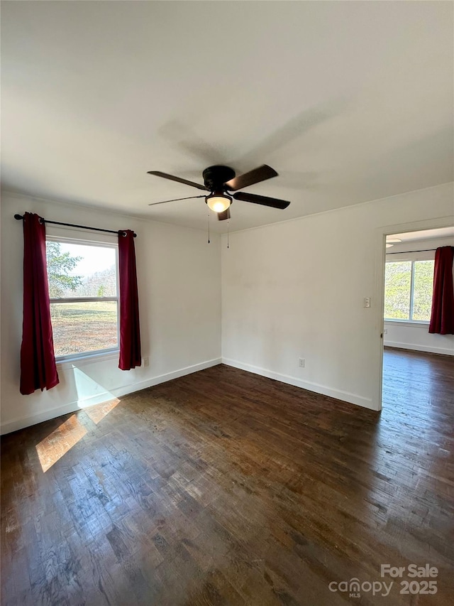 empty room featuring a ceiling fan, baseboards, and dark wood-type flooring