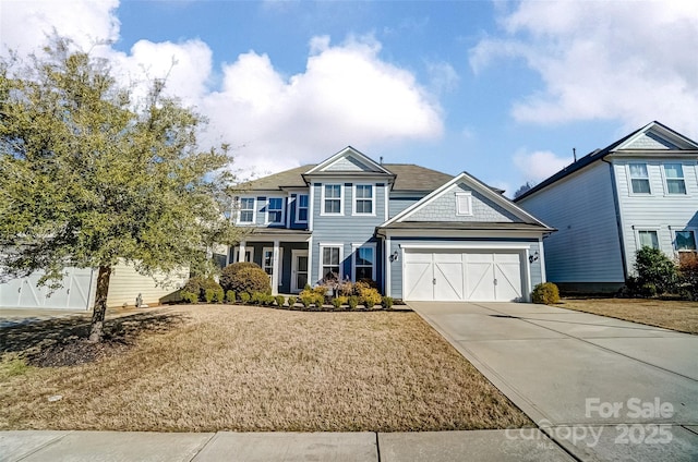 view of front of house with a garage, concrete driveway, and a front lawn