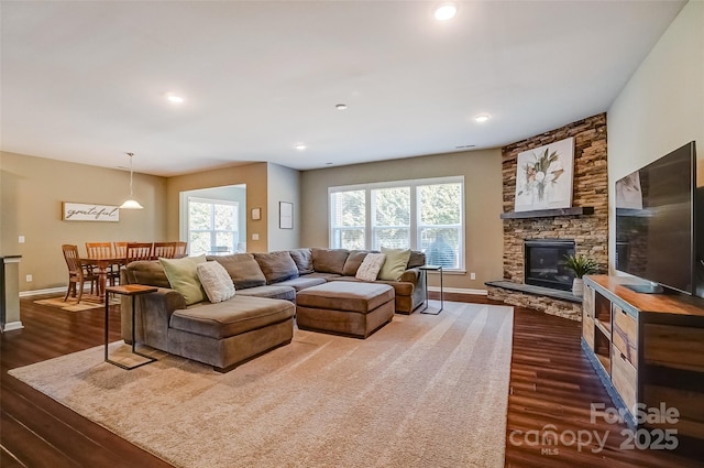 living room featuring recessed lighting, baseboards, a fireplace, and dark wood-style flooring