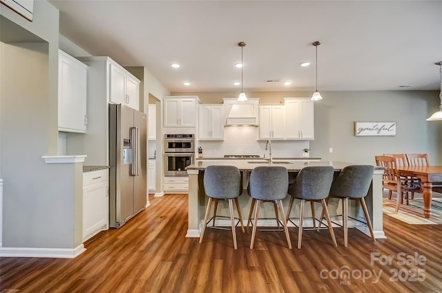 kitchen with dark wood finished floors, white cabinets, stainless steel appliances, and custom range hood