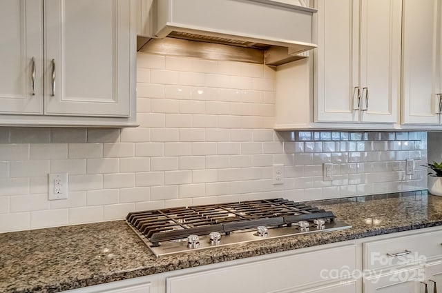 kitchen with tasteful backsplash, custom exhaust hood, white cabinets, and stainless steel gas cooktop