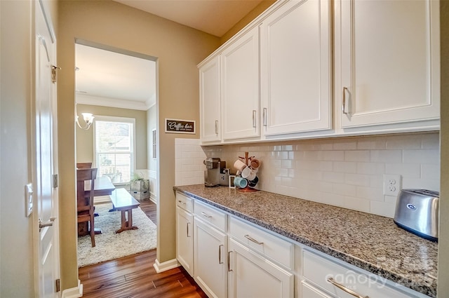 kitchen with dark wood-type flooring, ornamental molding, tasteful backsplash, white cabinetry, and light stone countertops