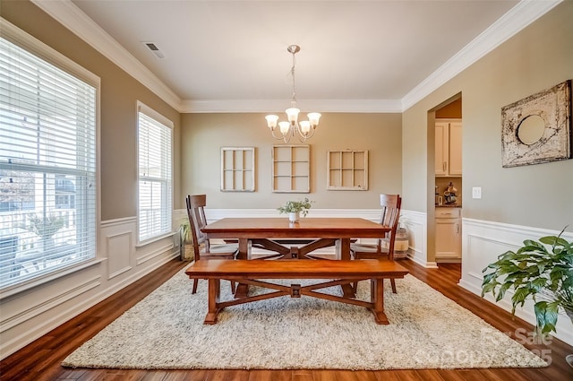 dining area featuring a wainscoted wall, a notable chandelier, and dark wood-style flooring