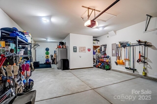 garage featuring electric panel, baseboards, a garage door opener, and freestanding refrigerator