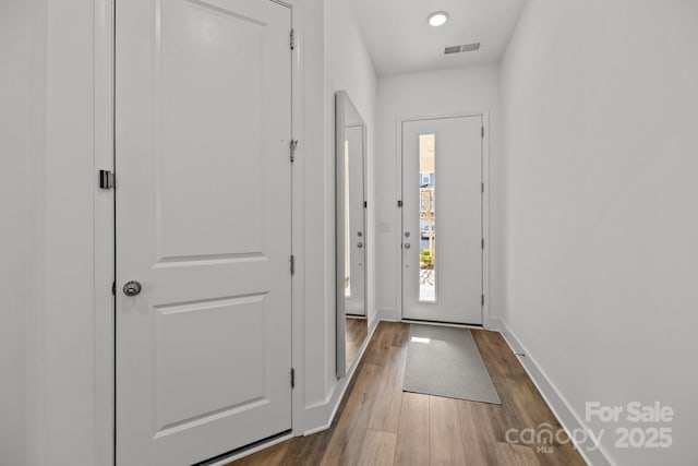 doorway to outside with dark wood-style floors, baseboards, and visible vents