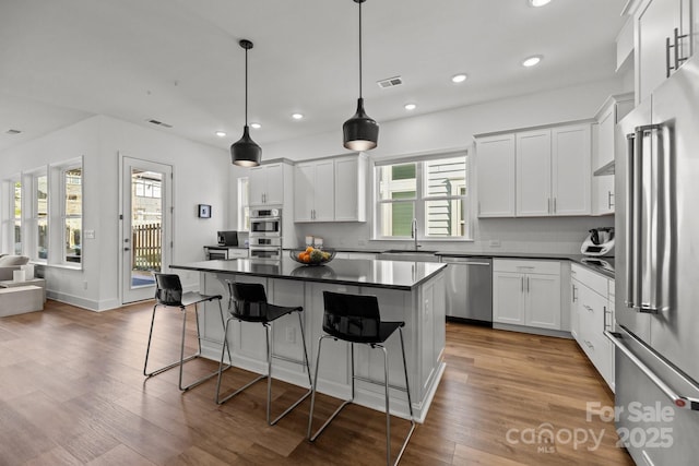 kitchen with dark countertops, visible vents, appliances with stainless steel finishes, and a sink