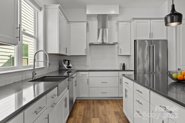 kitchen with black electric stovetop, white cabinets, a sink, wall chimney range hood, and high end refrigerator