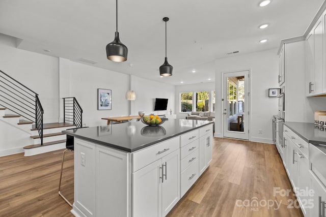 kitchen with dark countertops, wood finished floors, visible vents, and white cabinetry