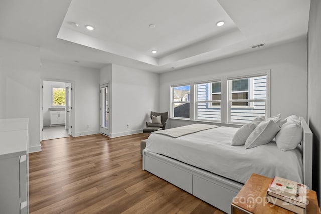 bedroom with recessed lighting, a raised ceiling, and wood finished floors