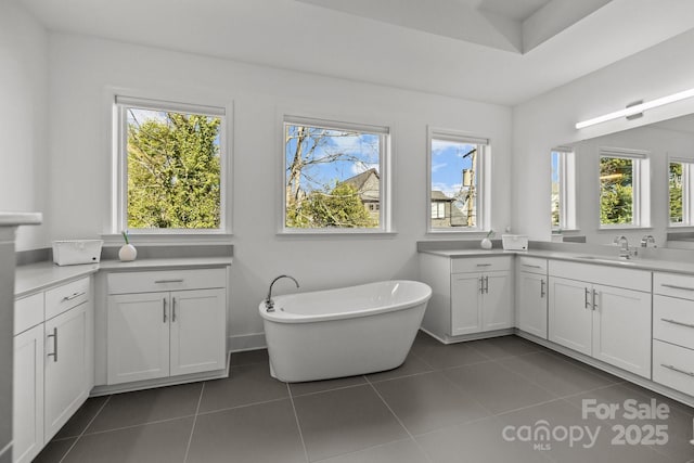 full bathroom with tile patterned flooring, a freestanding bath, and vanity