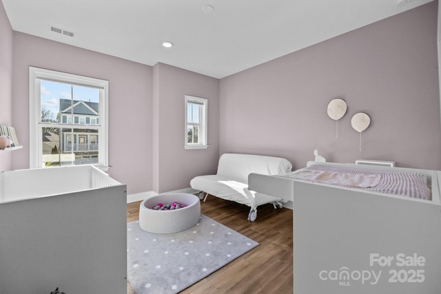 bedroom featuring wood finished floors, visible vents, and baseboards