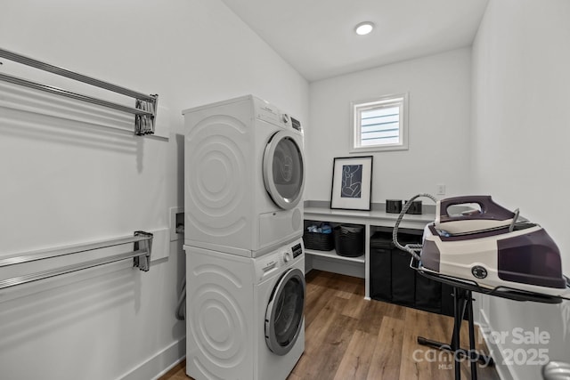 clothes washing area with laundry area, wood finished floors, and stacked washer and clothes dryer