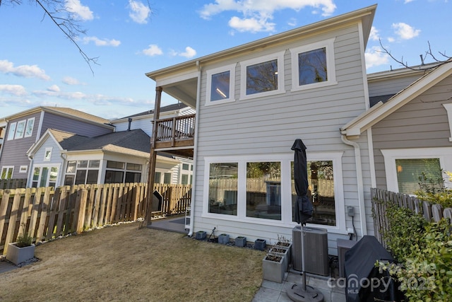 rear view of house with fence, a balcony, and central AC unit