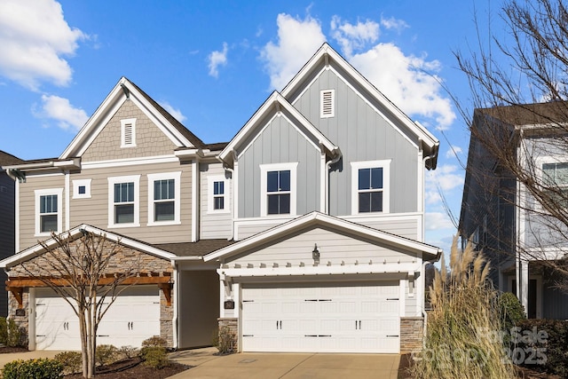 view of front of property with board and batten siding, stone siding, driveway, and a garage