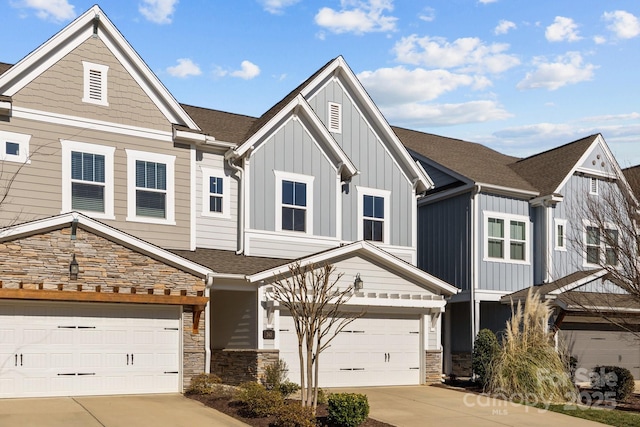 multi unit property featuring a garage, concrete driveway, stone siding, roof with shingles, and board and batten siding