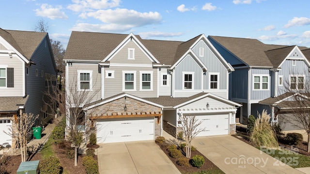 view of front of home featuring a garage, stone siding, board and batten siding, and concrete driveway