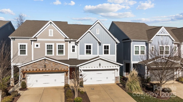 view of property featuring an attached garage, stone siding, board and batten siding, and concrete driveway