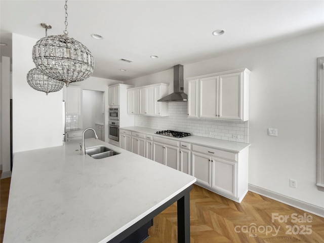 kitchen featuring wall chimney range hood, tasteful backsplash, gas cooktop, and a sink