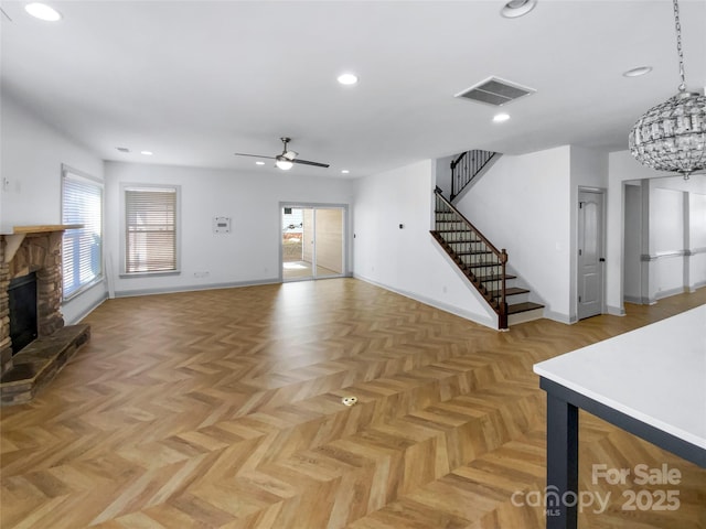 living area with recessed lighting, ceiling fan with notable chandelier, a fireplace, visible vents, and stairway