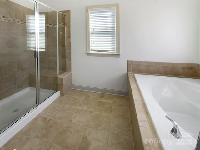 bathroom with baseboards, tile patterned floors, a garden tub, and a shower stall