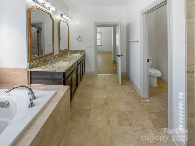 full bathroom with toilet, double vanity, a sink, and a bath