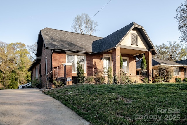view of front of house with brick siding, a front lawn, and concrete driveway