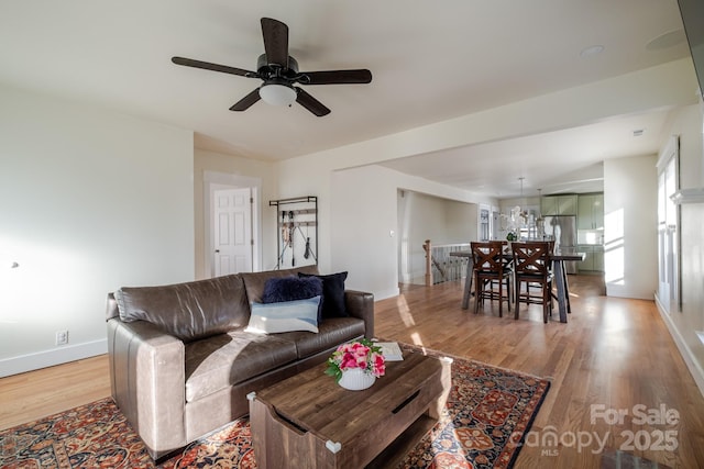 living room with light wood-style flooring, baseboards, and ceiling fan