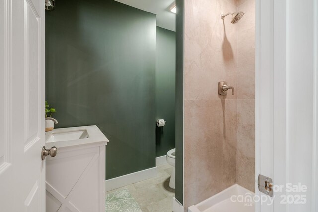 full bath with a tile shower, toilet, and vanity