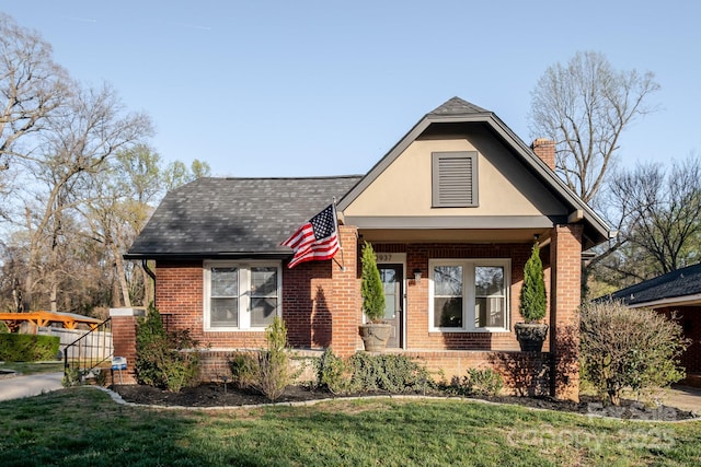 view of front of property featuring brick siding, a chimney, a front lawn, and roof with shingles