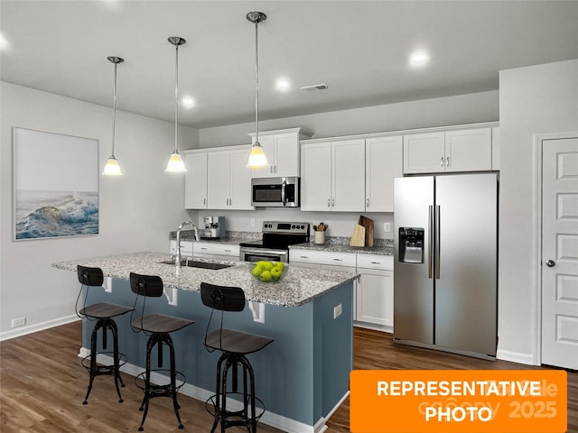 kitchen with appliances with stainless steel finishes, a sink, white cabinetry, and a kitchen breakfast bar