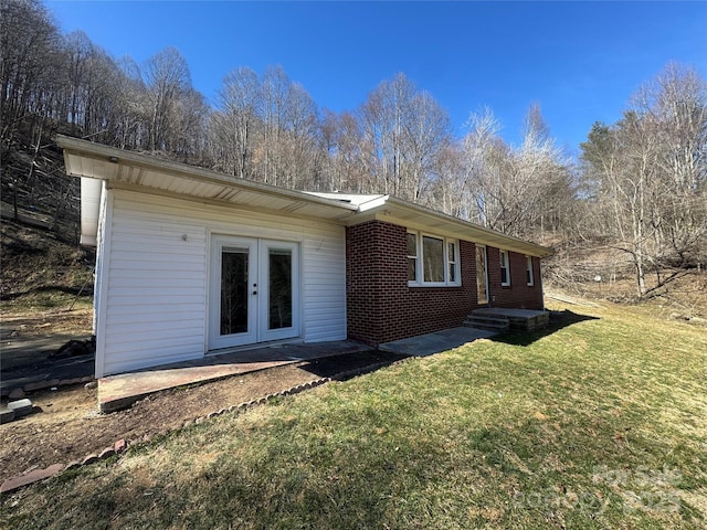 back of house with brick siding, a yard, and french doors