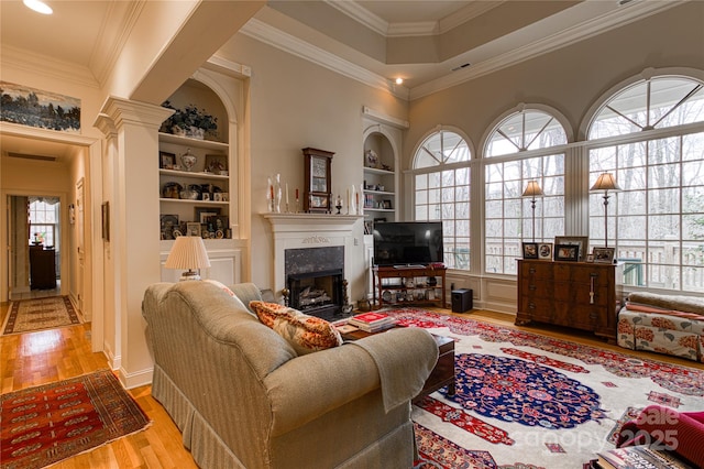 living room with plenty of natural light, ornamental molding, built in shelves, and wood finished floors