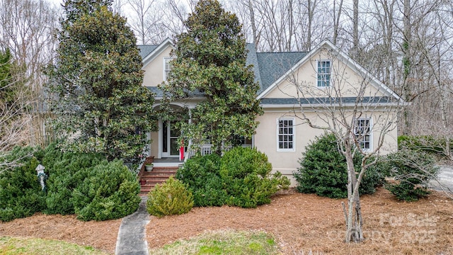 view of front of house featuring stucco siding and roof with shingles