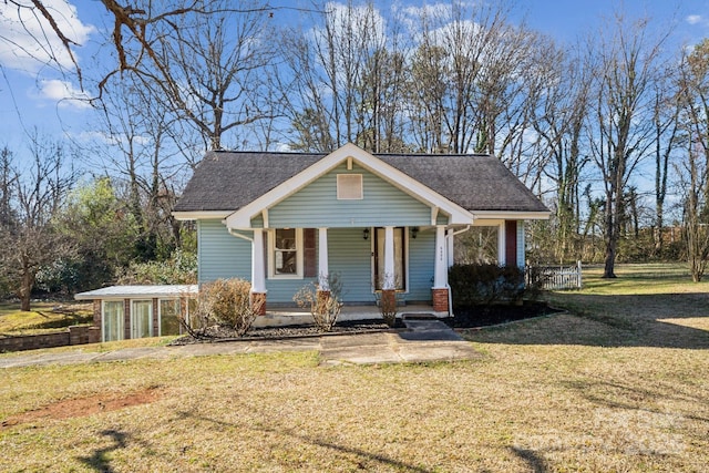 view of front of home with a front yard, covered porch, and roof with shingles