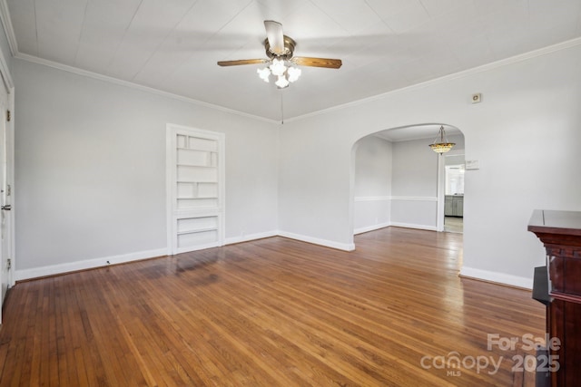 unfurnished living room with ornamental molding, a ceiling fan, hardwood / wood-style floors, arched walkways, and baseboards