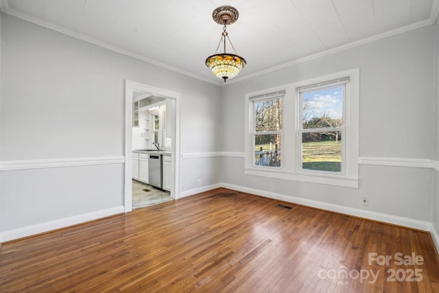 unfurnished room with visible vents, ornamental molding, baseboards, and wood-type flooring