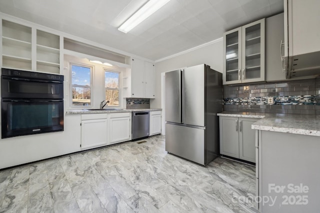 kitchen featuring light stone counters, a sink, stainless steel appliances, glass insert cabinets, and backsplash